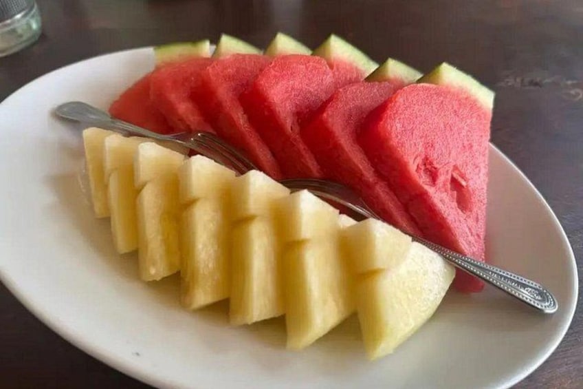 A plate with sliced watermelon and pineapple arranged on a white plate. 5