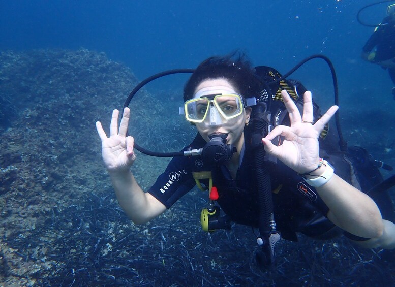 A diver underwater making a peace sign with their hands. 2