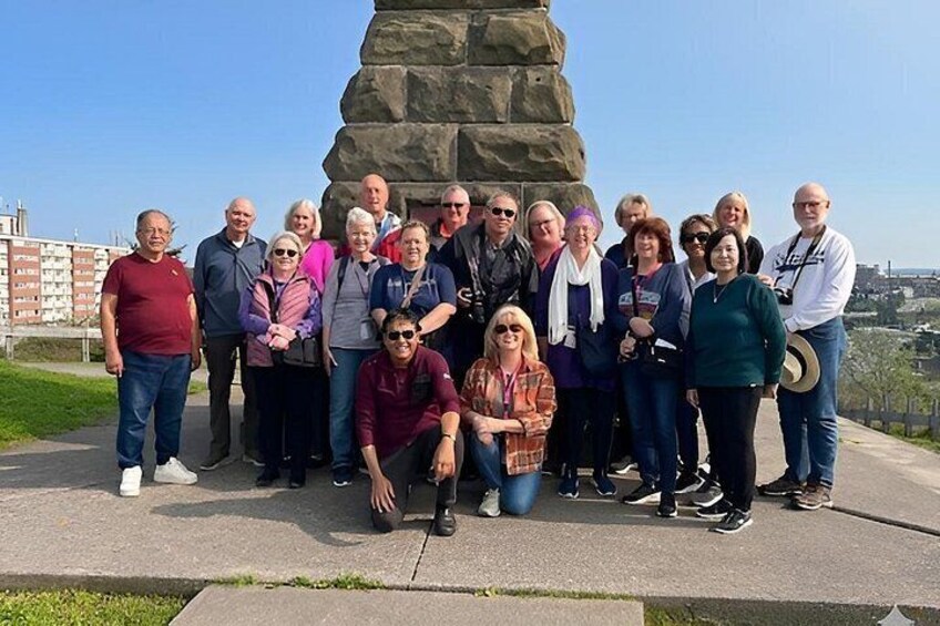 Eine Gruppe von Menschen steht vor einem großen Steinmonument. 5