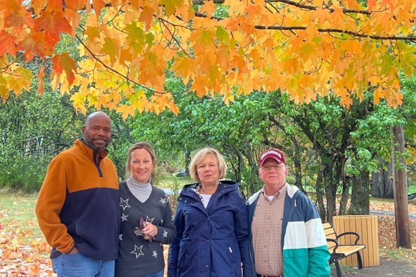 A group of people standing in a park with autumn leaves. 3