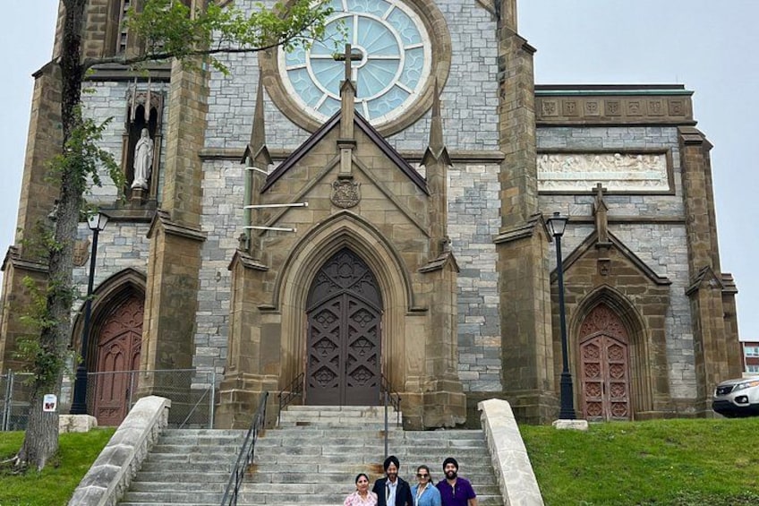 A church with a large circular window, a cross, and a statue on the tower. 5