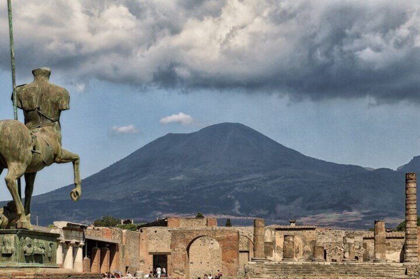 A statue of a man on horseback, ancient ruins, and a mountain in the background. 5