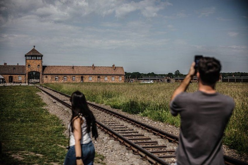 A railway track, a building with a tower, and a person taking a photo. 3