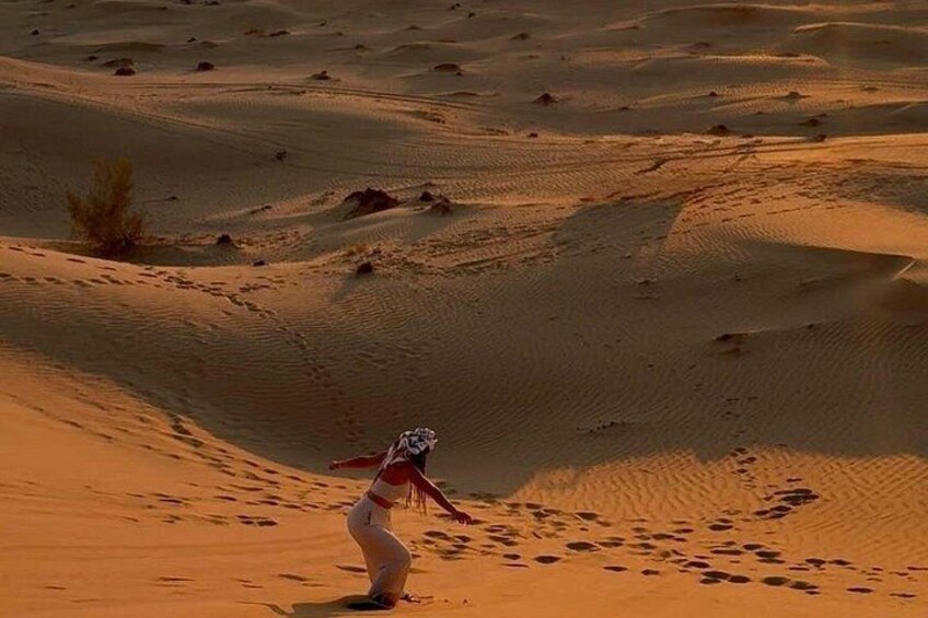 A person walking on a sandy desert landscape with dunes and sparse vegetation. 5