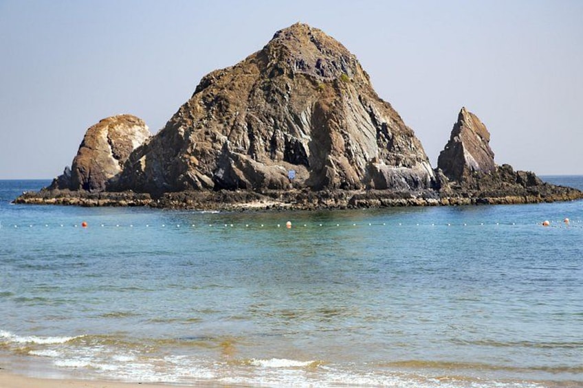 A rocky island with clear blue water and a sandy beach. 4