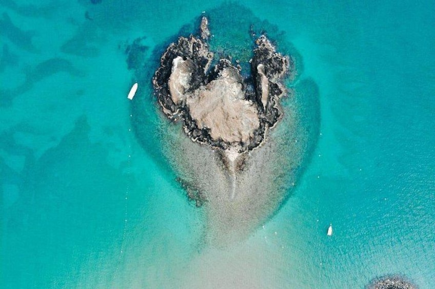 An aerial view of a small island with clear turquoise waters and a white boat near the shore. 3