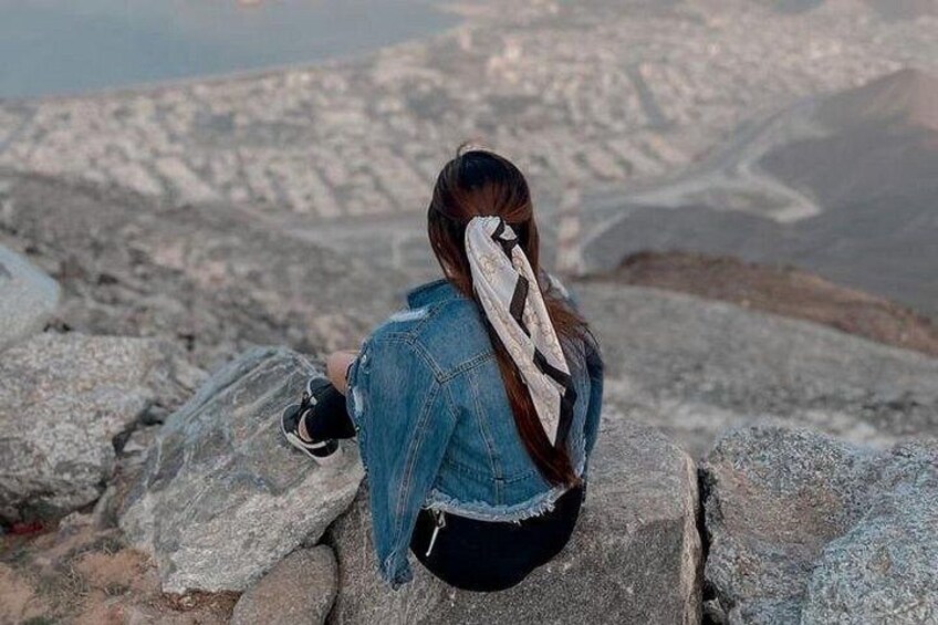 A person sitting on rocks with a mountainous landscape in the background. 2