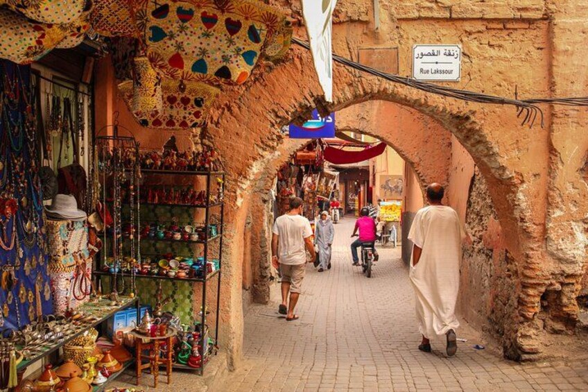 Una calle estrecha flanqueada por tiendas, un arco y un letrero en árabe. 1