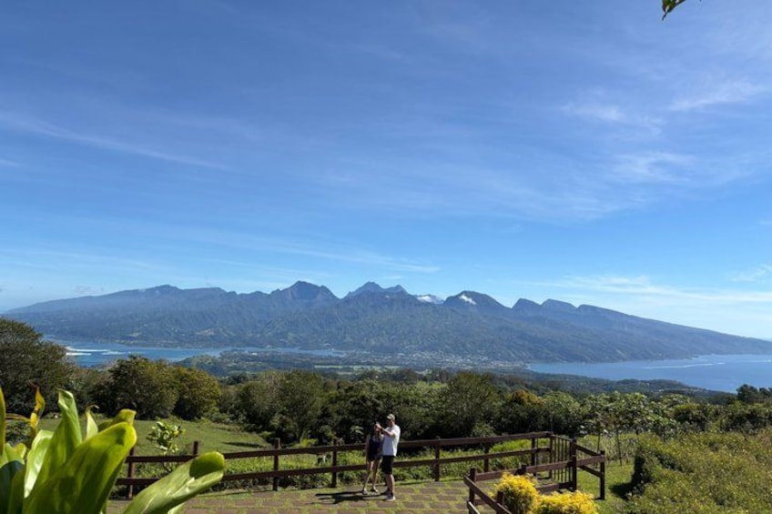 Una persona parada sobre una plataforma de madera, con vista a un paisaje montañoso y una masa de agua al fondo. 3