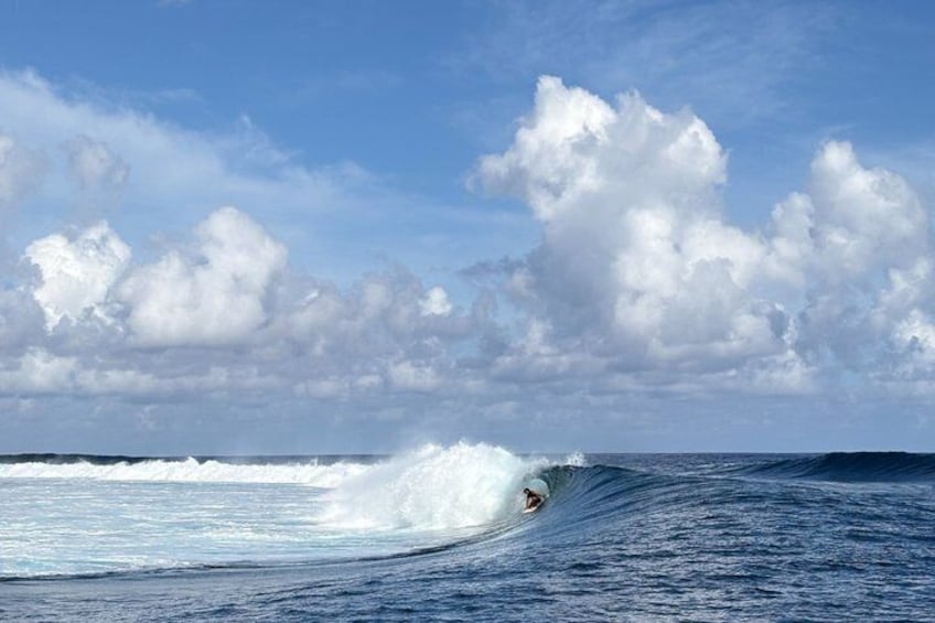 A surfer riding a wave in the ocean under a partly cloudy sky. 1