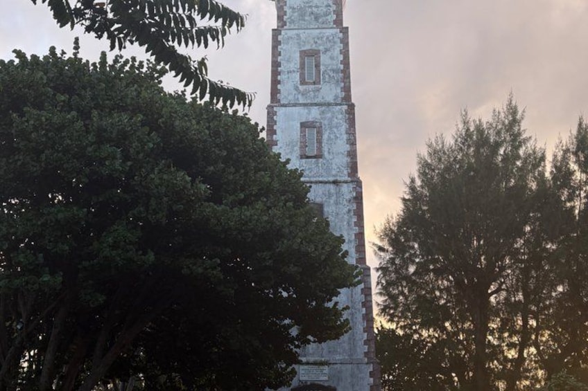 Una torre alta y erosionada, con múltiples ventanas, rodeada de follaje denso. 2