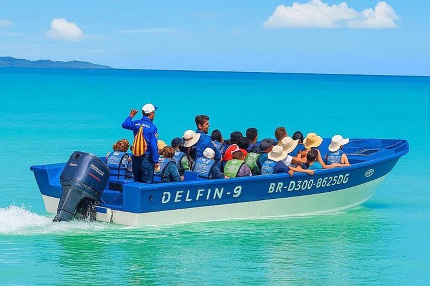 A boat named DELFIN-9 with passengers wearing life jackets and hats, moving on turquoise water. 4