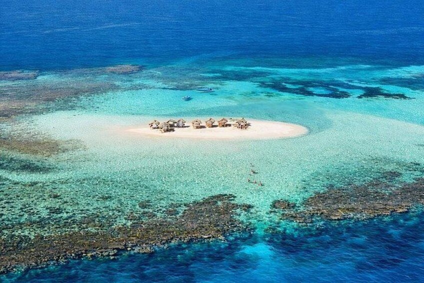 An aerial view of a small island with clear turquoise waters and a sandy beach. 5