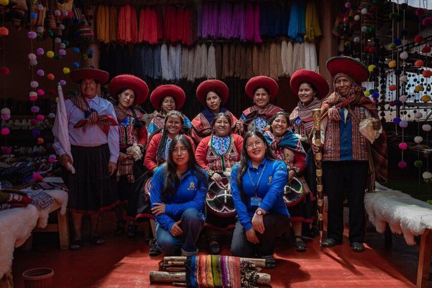 Un grupo de personas con atuendos tradicionales, telas coloridas y sombreros, reunidas en un espacio interior decorado. 1