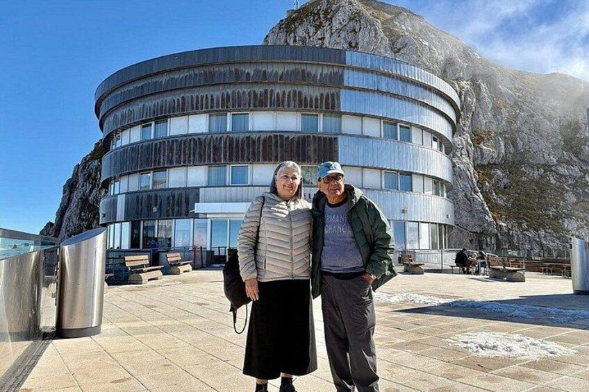 Un edificio moderno con fachada curva, montañas rocosas al fondo y cielo despejado. 5