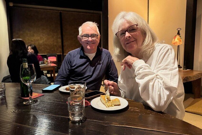 Two people sitting at a table with a plate of food and a glass of water. 2