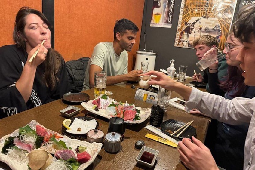 A group of people dining at a restaurant with various dishes and condiments on the table. 5