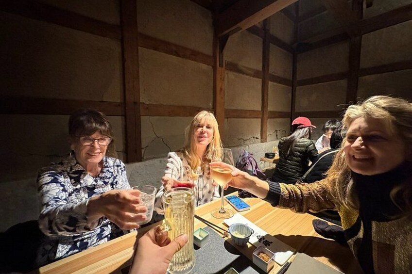 A group of people toasting at a wooden table in a rustic setting. 4