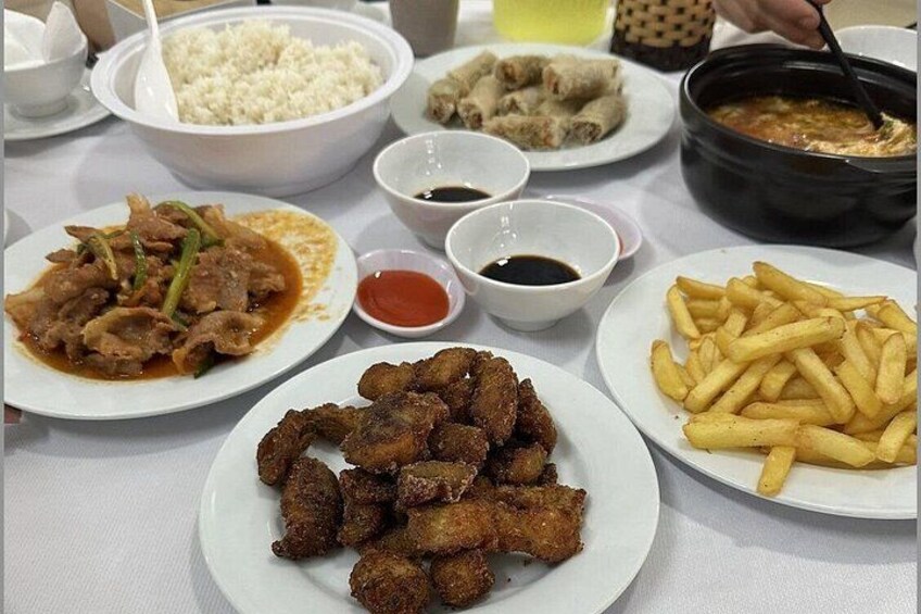 A table with various dishes including fried chicken, rice, and French fries. 4
