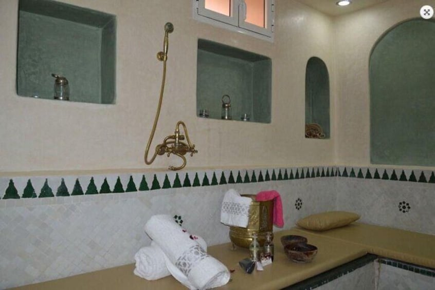 A bathroom with a shower, towel rack, and decorative tiles. 1