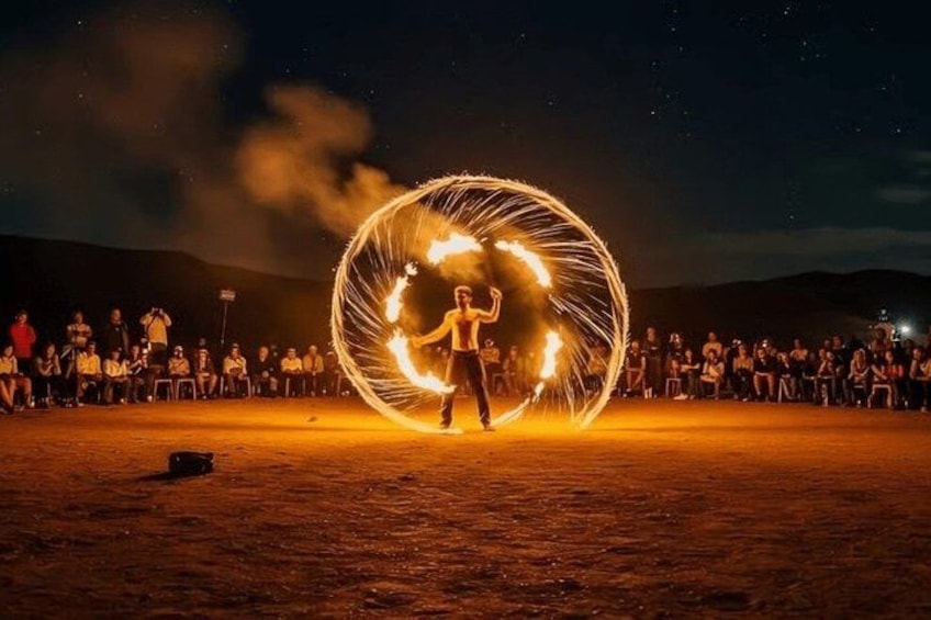 Une personne réalisant un numéro de jonglage avec le feu, en utilisant un grand cercle enflammé, dans un décor désertique, la nuit. 5