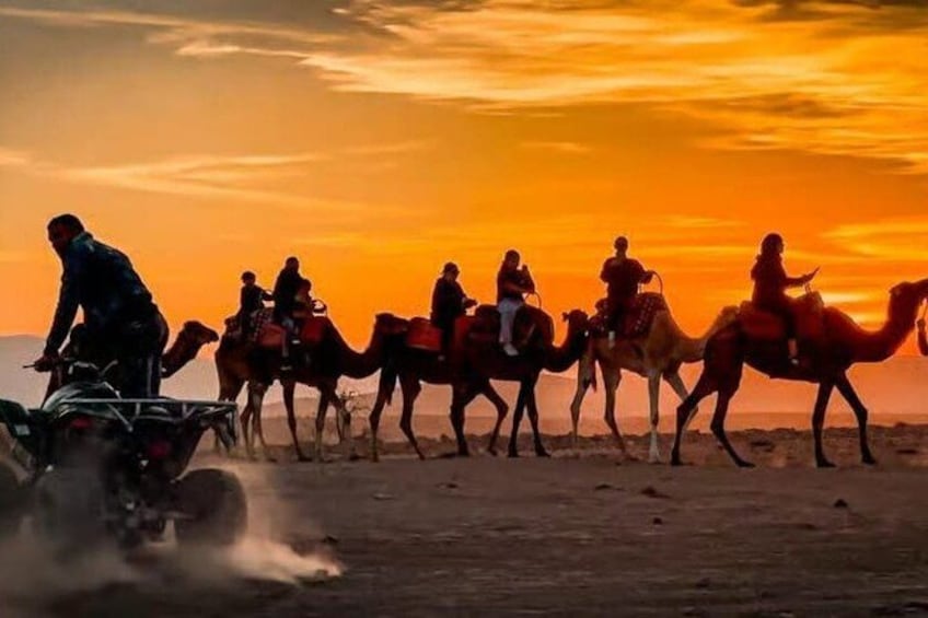 Un groupe de personnes chevauchant des chameaux dans le désert au coucher du soleil. 1