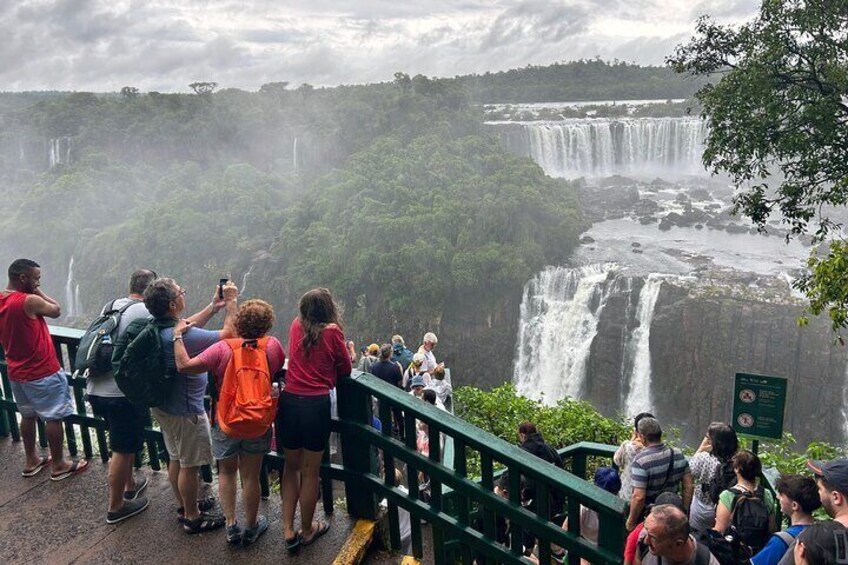 Un grupo de personas observando una cascada imponente desde una plataforma panorámica. 1