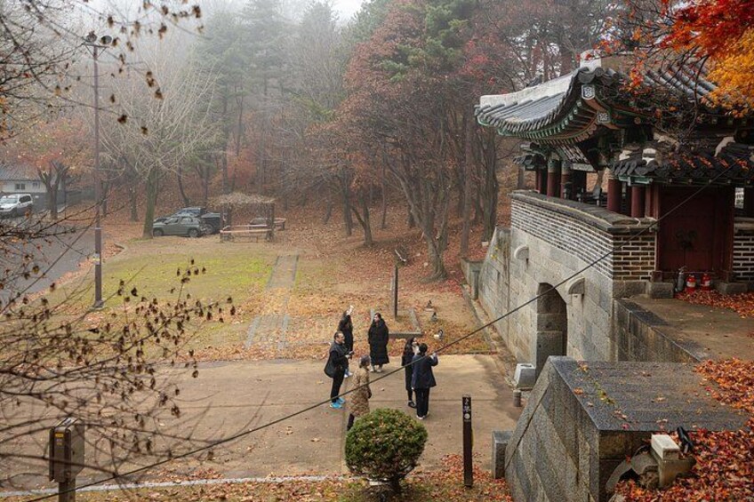 A traditional Korean temple with a stone bridge, autumn leaves, and a foggy atmosphere. 5
