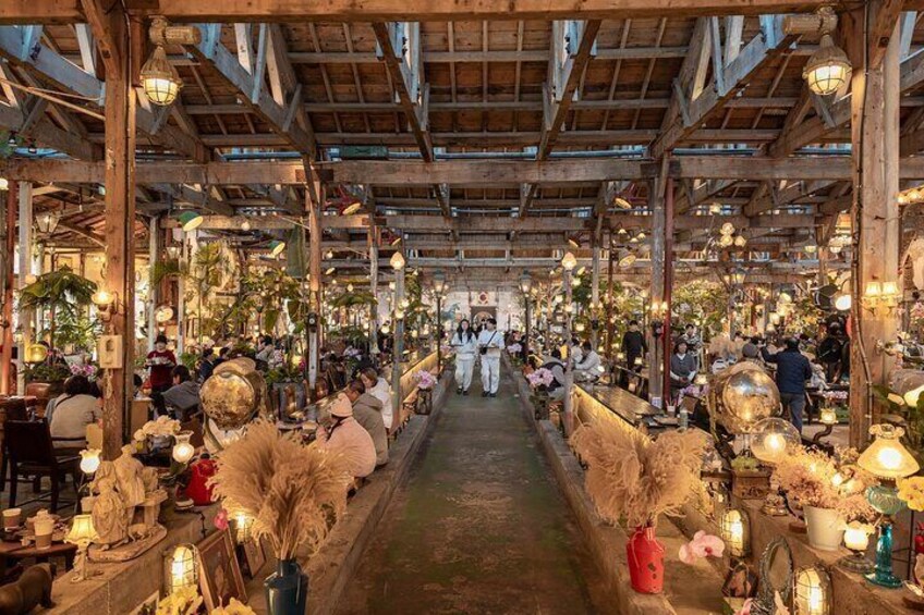 Un marché couvert avec des poutres en bois, des lanternes et divers étals. 1
