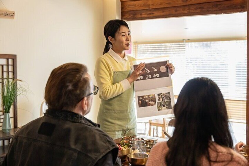 A person presenting a menu to a group of seated individuals. 1