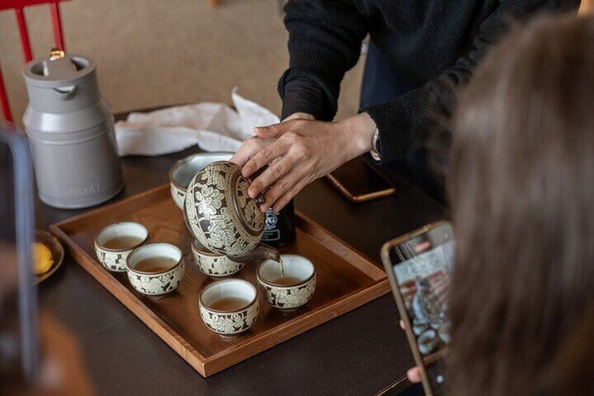 A person pouring tea into cups on a tray. 5