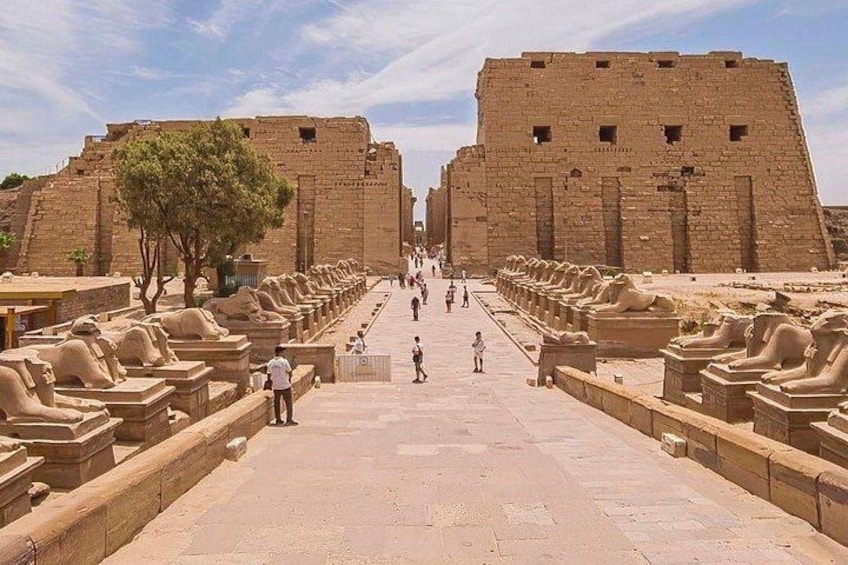 A large ancient Egyptian temple with sphinx statues lining the walkway. 5