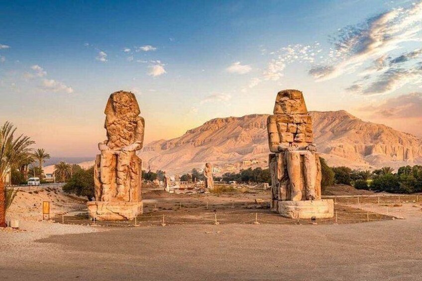 Dos grandes estatuas de piedra en un paisaje desértico con montañas al fondo. 2