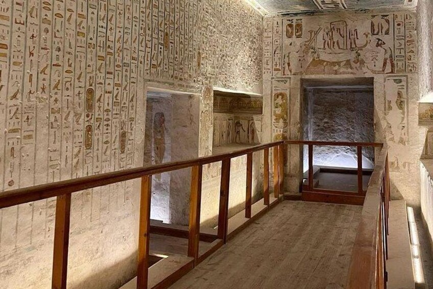 An interior with hieroglyphic walls, a wooden railing, and a stone floor. 3