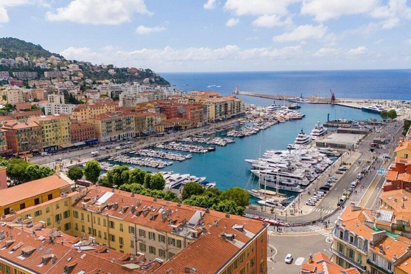 A coastal cityscape with a marina, buildings, and a bridge. 2