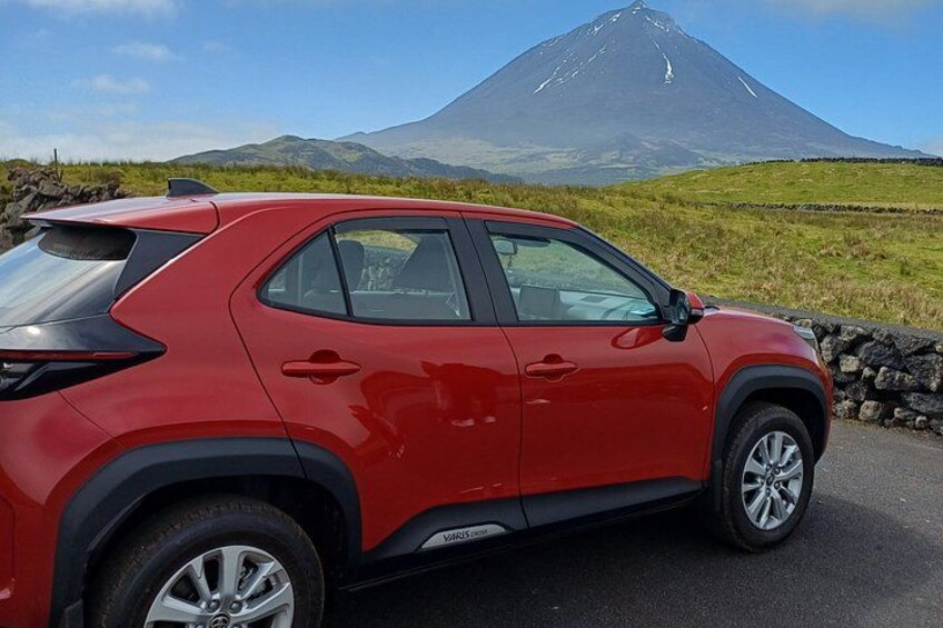 En röd SUV står parkerad på en väg med ett berg i bakgrunden. 1