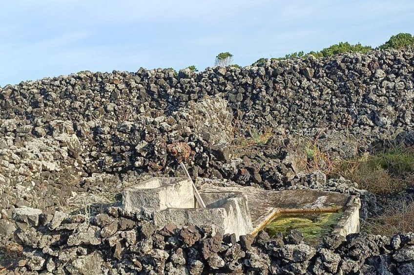 A rocky landscape with a stone structure and a small pool. 2