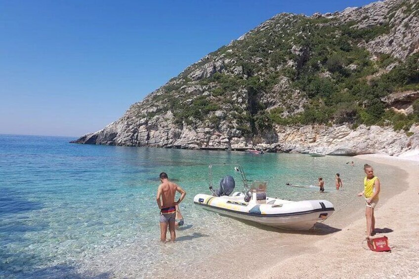 Une plage bordée d’une eau turquoise et limpide, une colline rocheuse et un petit bateau échoué sur le sable. 4