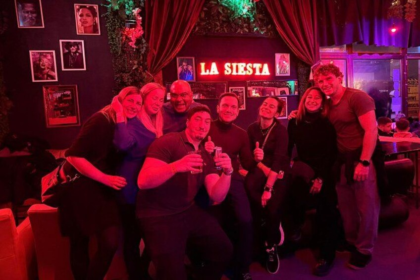 A group of people in a dimly lit room with a sign that reads 'LA SIERRA'. 5