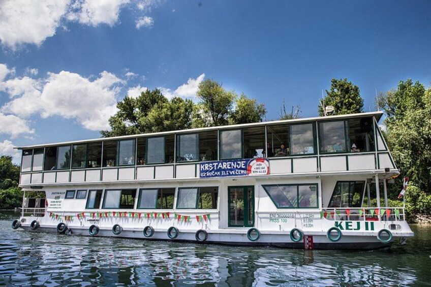 A double-deck river cruise boat with 'KRSTARENJE' signage, 'KEJI' branding, and a green and white color scheme. 2