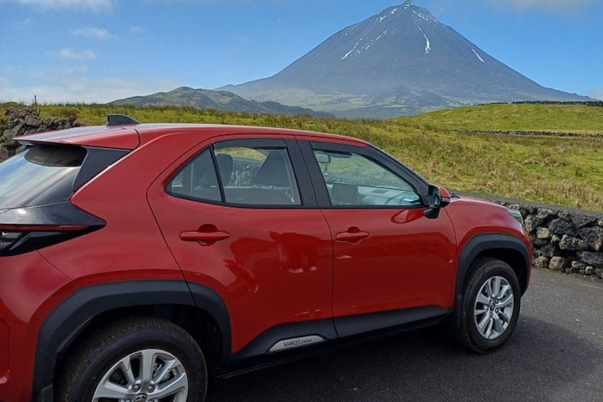 A red SUV parked on a road with a mountain in the background. 1