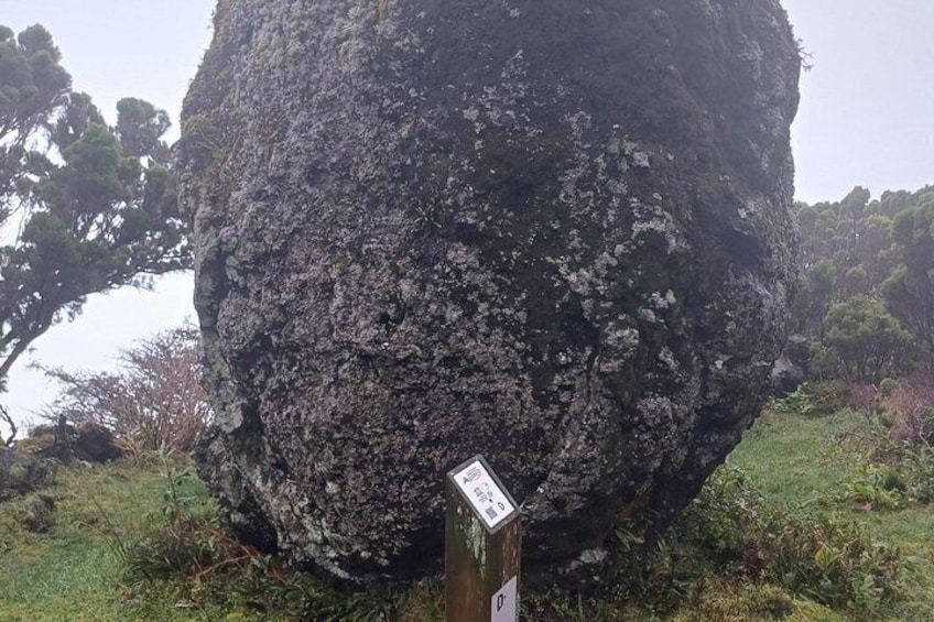 A large rock formation with a signpost in front. 2