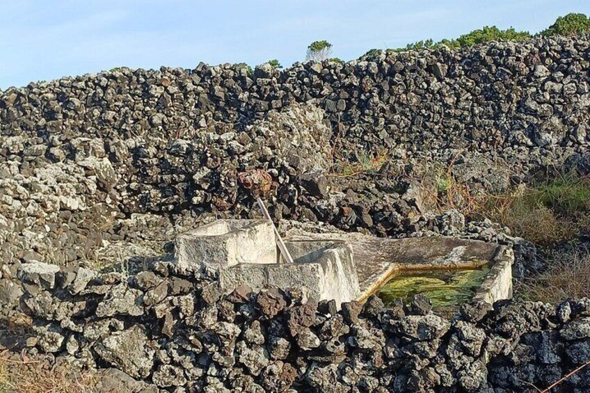 A rocky landscape with a stone structure and a small pond. 3