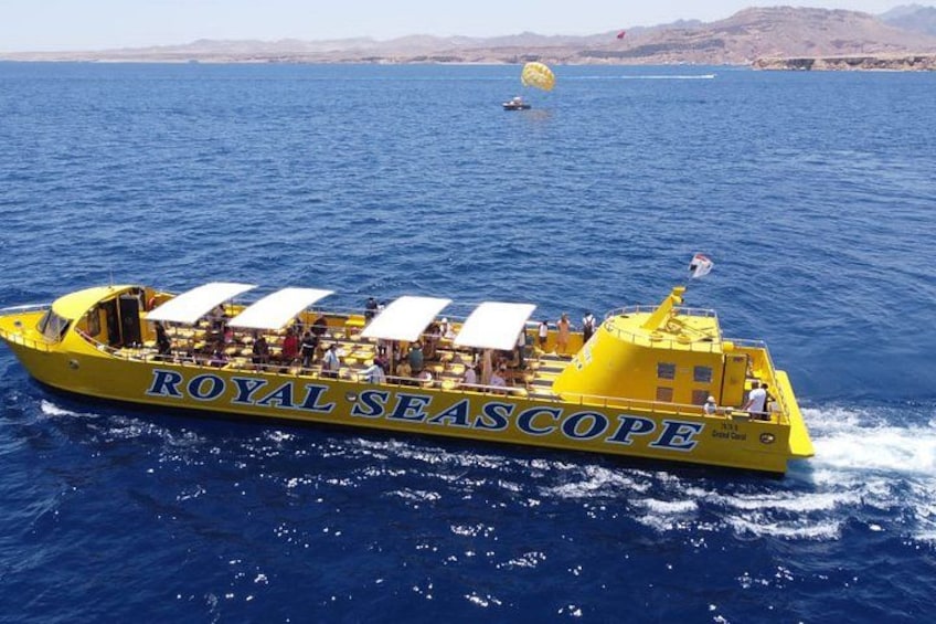 A yellow boat named 'ROYAL SEASCOPE' on the water with a parasail in the background. 2