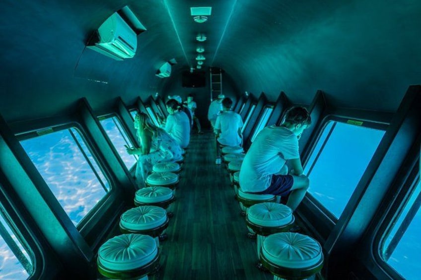 A ship's interior with rows of windows, people seated, and a ladder leading to the deck. 4