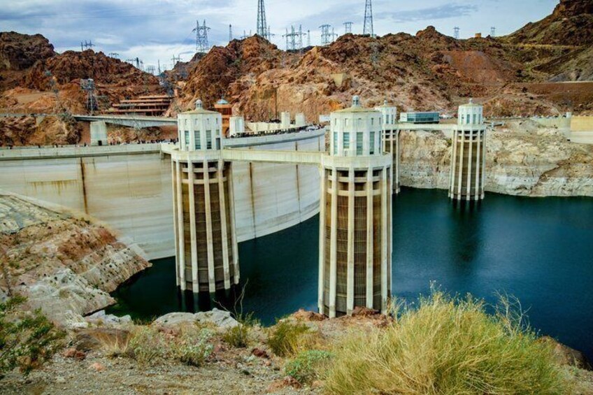 A dam with water reservoirs, transmission towers, and rocky terrain. 3