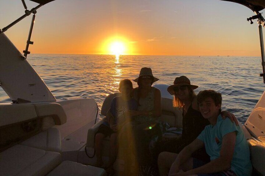 A boat with people sitting at the bow during sunset. 5
