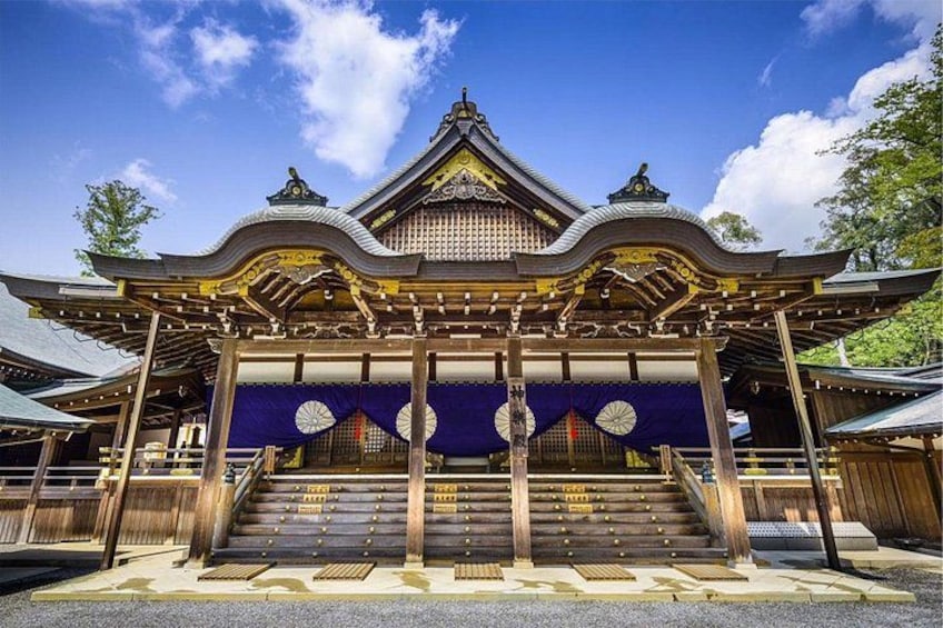 A traditional Japanese building with a curved roof, wooden structure, and a blue awning. 1