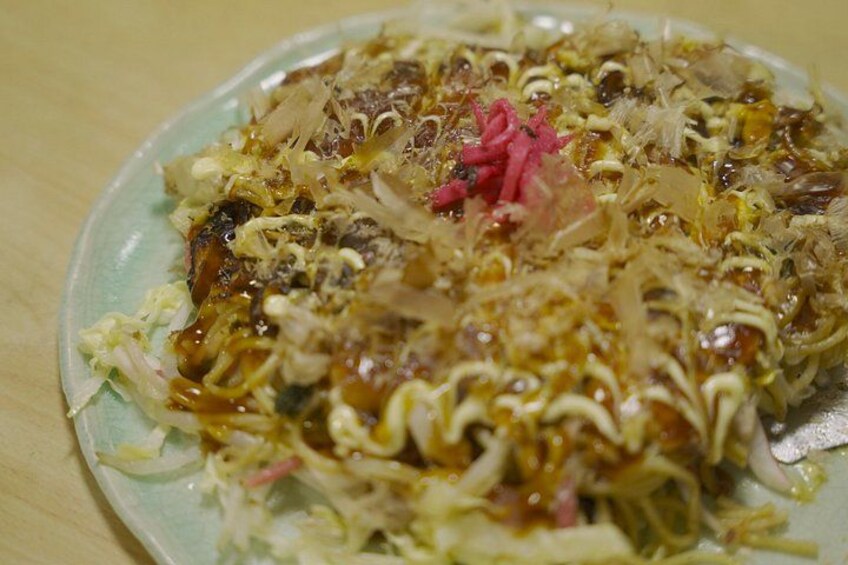 Une assiette d'okonomiyaki garnie de divers ingrédients. 1
