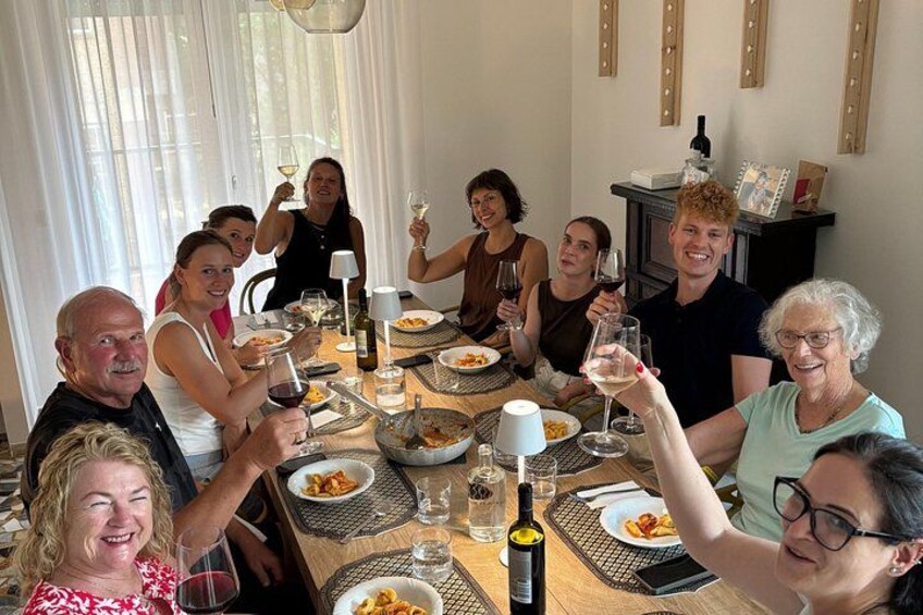 A group of people sitting around a table, toasting with wine glasses. 3